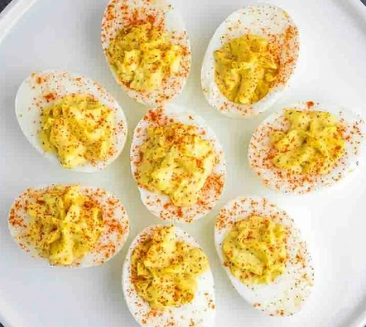 Plate of classic deviled eggs garnished with paprika and herbs