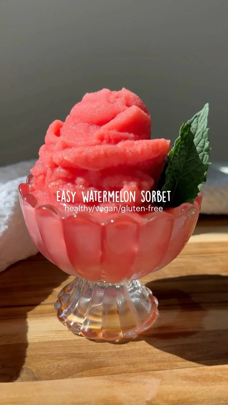 Bowl of homemade watermelon sorbet garnished with fresh mint leaves.